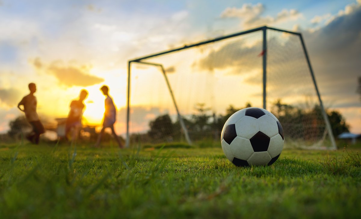 En fotboll på en fotbollsplan i kvällssol